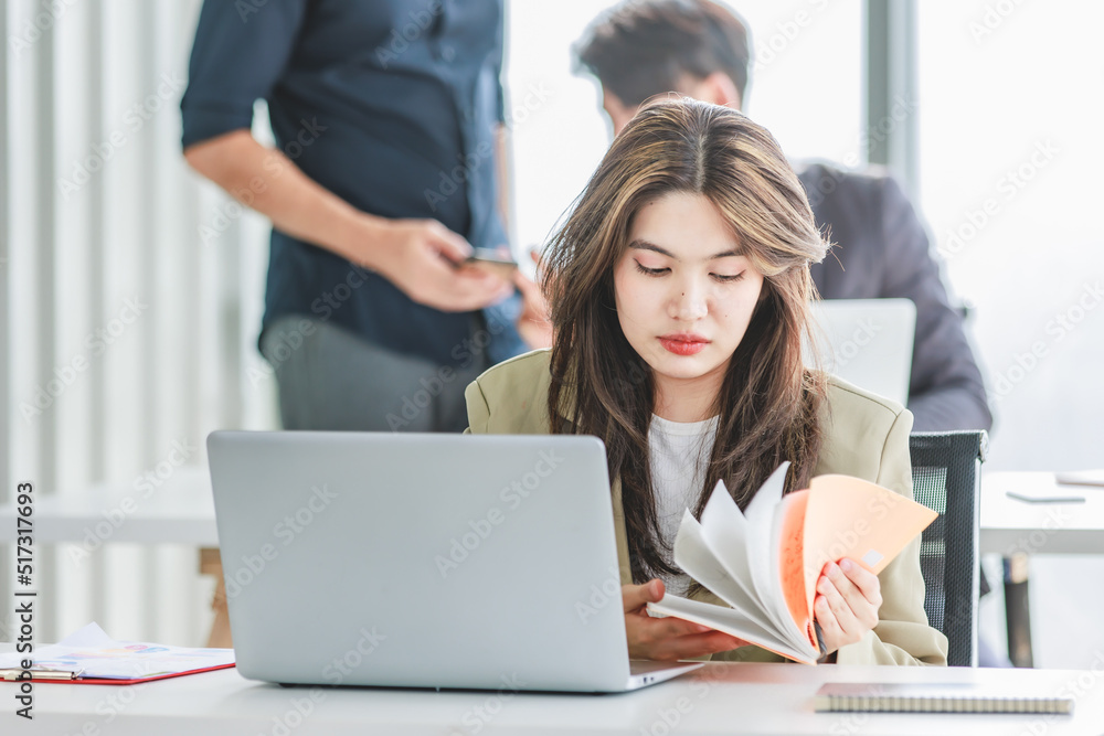 Closeup shot of millennial Asian young stressed depressed sleepy female businesswoman employee sitting holding hand on messy hair working on workstation desk via laptop notebook computer in office Closeup shot of millennial Asian young stressed depressed sleepy female businesswoman employee sitting holding hand on messy hair working on workstation desk via laptop notebook computer in office