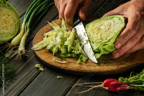 Cutting fresh cabbage by chef hands before preparing national or vegetarian food. Peasant food