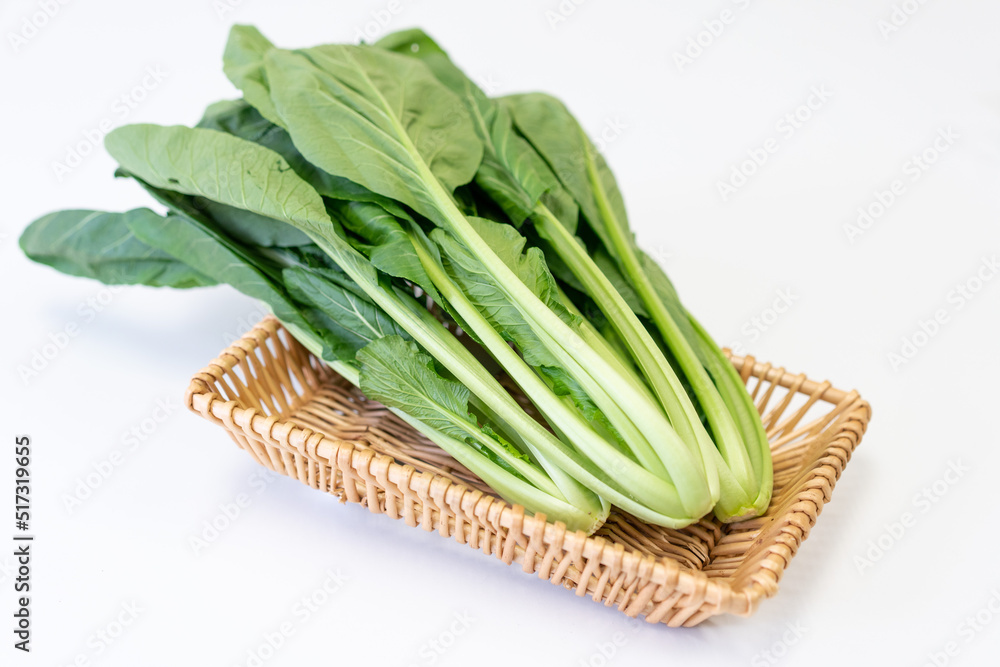 The fresh vegetables in the basket are placed on the white table The fresh vegetables in the basket are placed on the white table