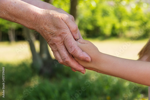 Close-up, the hands of an old woman hold in her hands the palms of a little girl © Natallia