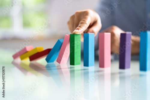 Businessperson Hand Stopping Colorful Blocks From Falling