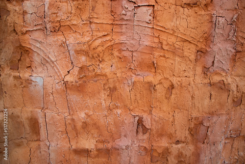 The texture of a red concrete wall with cracks and scratches can be used as a background