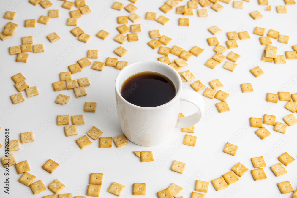 Coffee in a white cup on the background of a scattered crispy cracker on a white background Coffee in a white cup on the background of a scattered crispy cracker on a white background