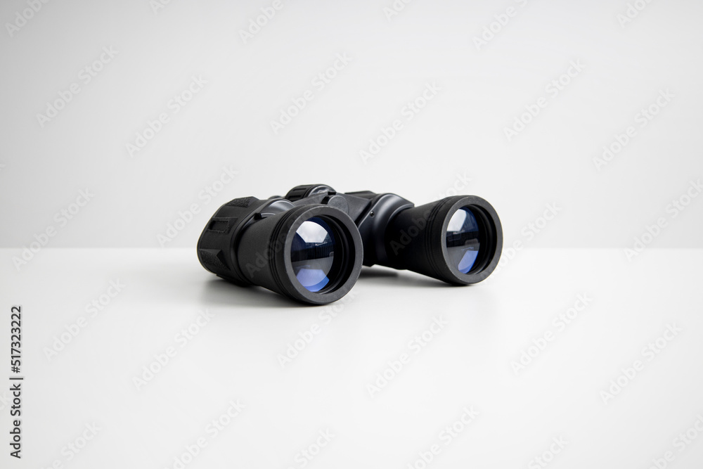Black binoculars lying on a white background. Side view