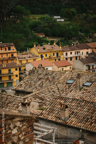 Old brown tiles on the roof of an old house in the Italian province - the village of Nerola. In the background are yellow and orange Italian houses and a green forest. photo