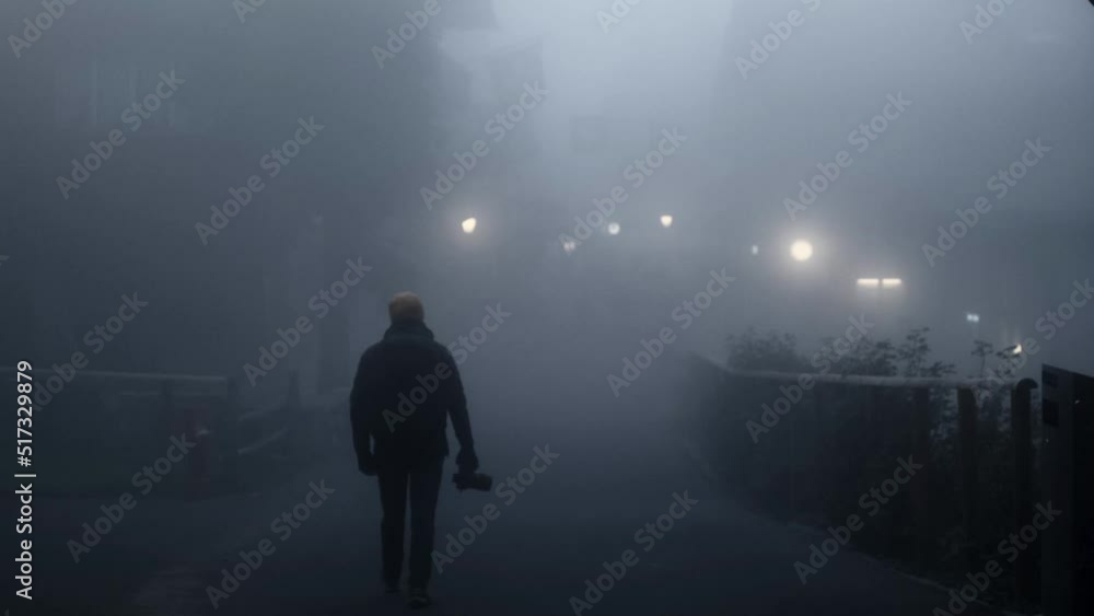A man walks with a backpack in a thick fog. Concept of a ghost town or a horror movie vibes. A man walks with a backpack in a thick fog. Concept of a ghost town or a horror movie vibes.