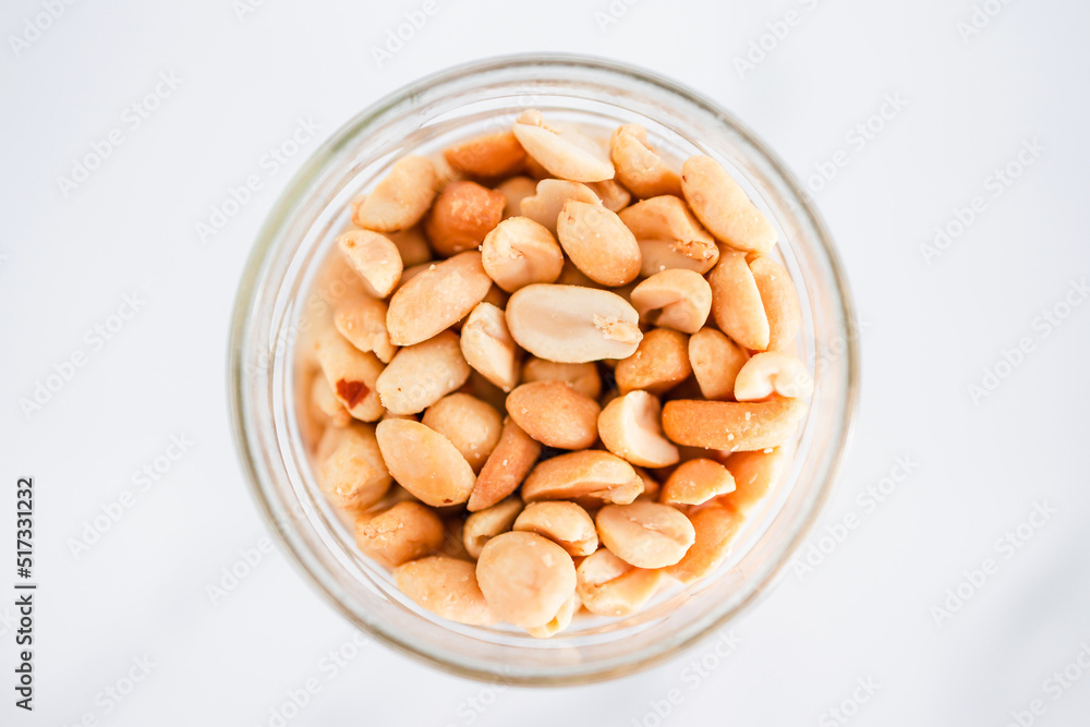 glass jar of peanuts on white marble background, healthy pantry ingredients glass jar of peanuts on white marble background, healthy pantry ingredients