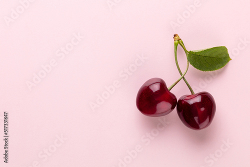 Cherry berries on a pastel background top view. Background with a cherry on a sprig, flat lay