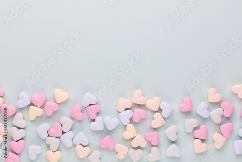 Composition with candy hearts on pastel blue background. © gitusik
