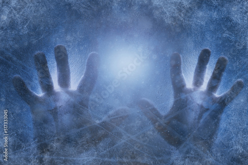 Human hands against frozen glass and blue background. Energy Crisis Concept. Cold winter 2022