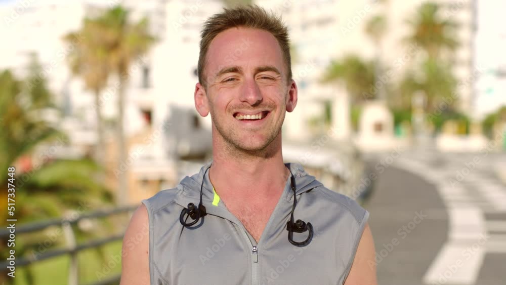 An active young man taking a break during his morning exercise routine. Portrait of one happy male athlete standing in a street after his workout or training. A fit runner smiling in a city An active young man taking a break during his morning exercise routine. Portrait of one happy male athlete standing in a street after his workout or training. A fit runner smiling in a city