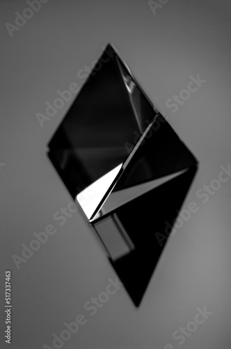 Shiny glass geometric figure in black and white. Black minimal still life image of an abstract shiny object.