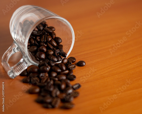 Coffee beans spiling out of a glass cup photo