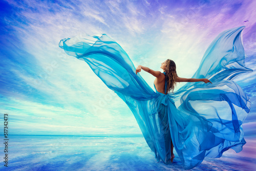 Fototapeta Woman in Blue Dress Flying on Wind looking at Sky and Sea