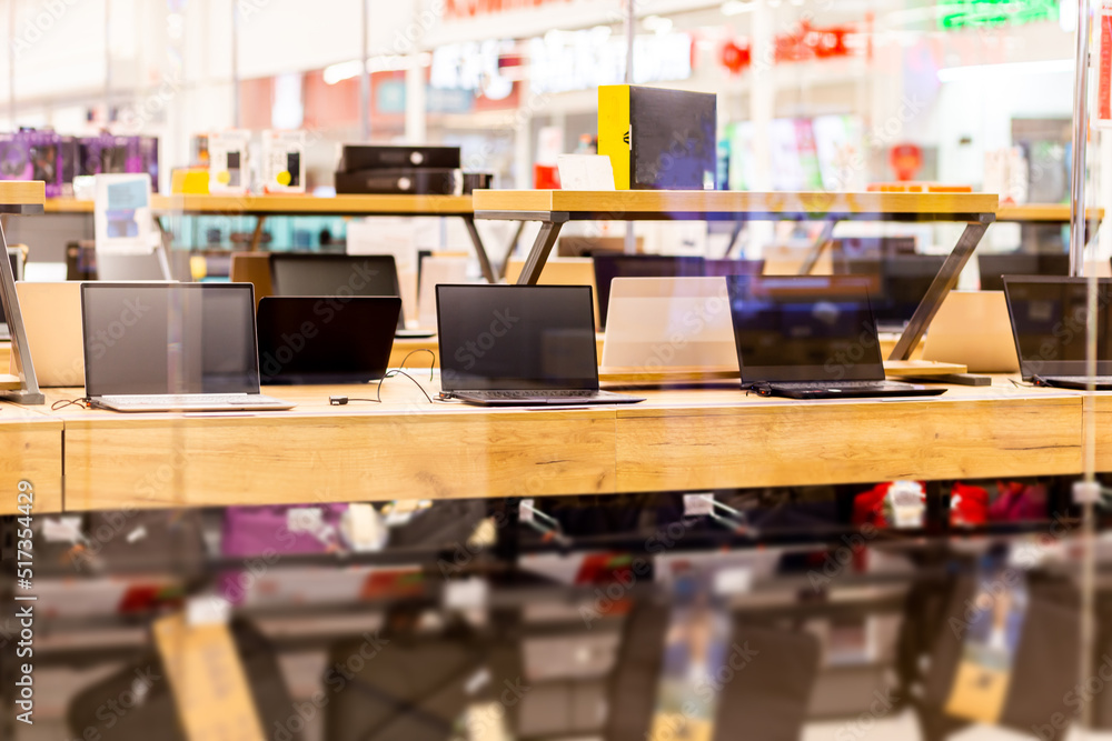 A sample of laptops in a shop window behind glass on a blurred background