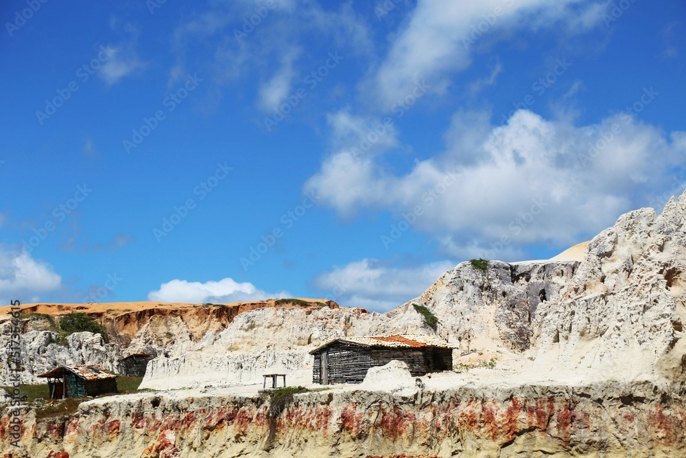 Poor house on the multicolored cliff. Hut used by fishermen for seasonal storage of boats and fishing gear. Cliffs of Morro Branco, Ceara state, Brazil