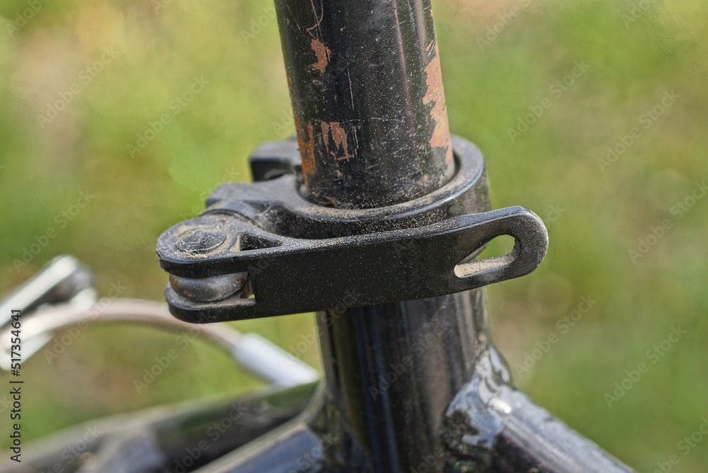 part of a metal tube with an iron clamp and a black plastic handle on a green background