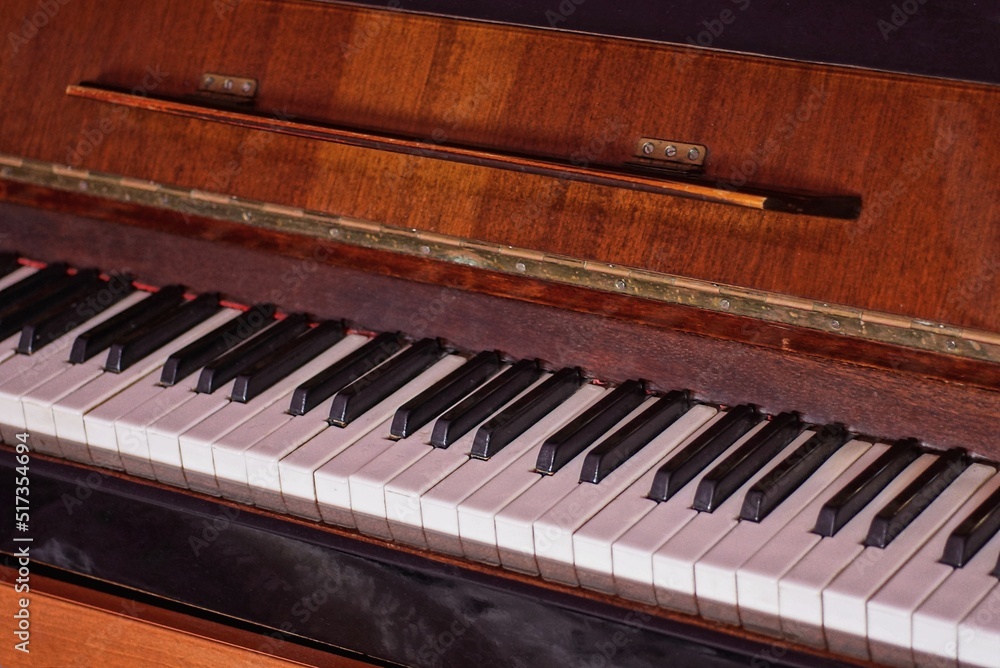 part of a brown old wooden piano with open white black keys in the room part of a brown old wooden piano with open white black keys in the room
