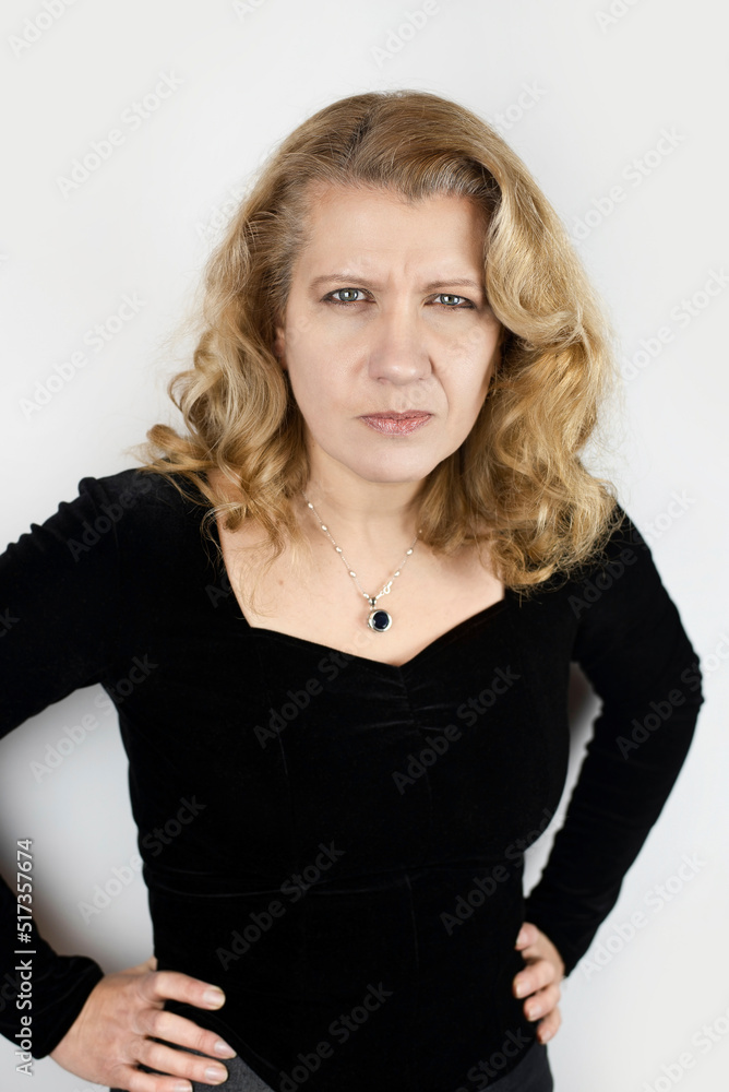 A mature woman is angry and sad on a light background, she is not happy that her hair is starting to turn gray, she wants to be young. The concept of health and beauty after 45 years A mature woman is angry and sad on a light background, she is not happy that her hair is starting to turn gray, she wants to be young. The concept of health and beauty after 45 years