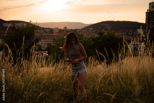 Young cheerful woman at sunset posing in the background of the city in the mountains.