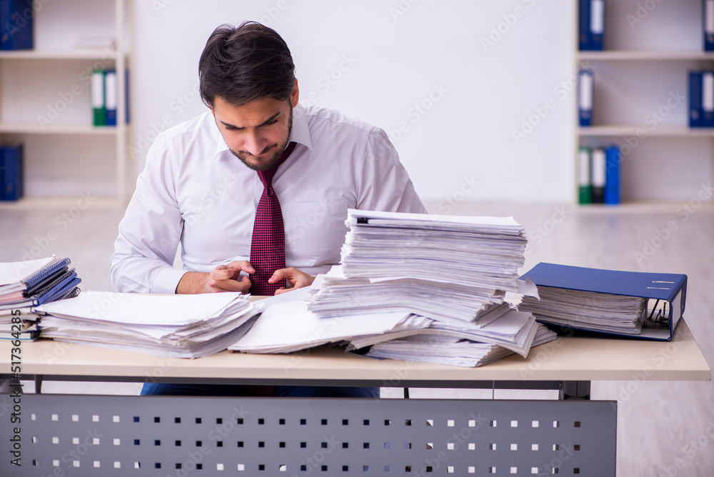 Young businessman employee unhappy with excessive work in the office Young businessman employee unhappy with excessive work in the office