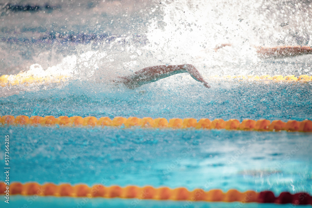Details with a professional male athlete swimming in an olympic swimming pool freestyle.