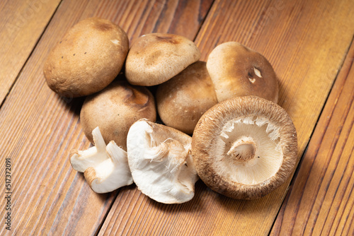 Multiple fresh shiitake mushrooms on wooden board