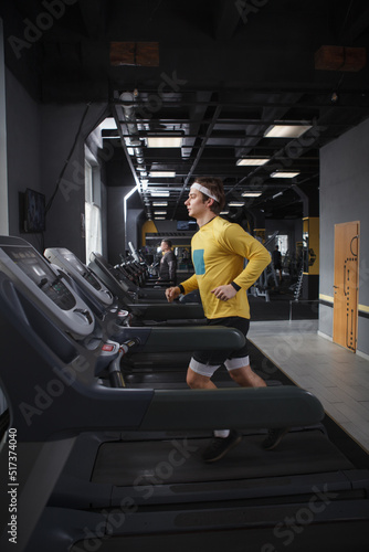 Vertical full length shot of a male runner on a treadmill at the gym