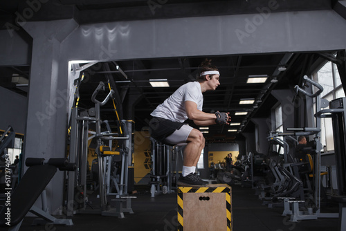 Fitness man jumping on a box at the gym