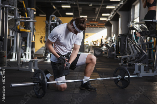 Male athlete preparing for barbell workout, wearing weightlifting belt © Ihor