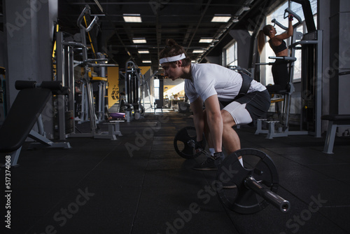 Strong athletic man exercising with barbell at functional training gym
