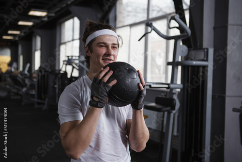 Handsome happy fitness man training with medicine ball at sports studio
