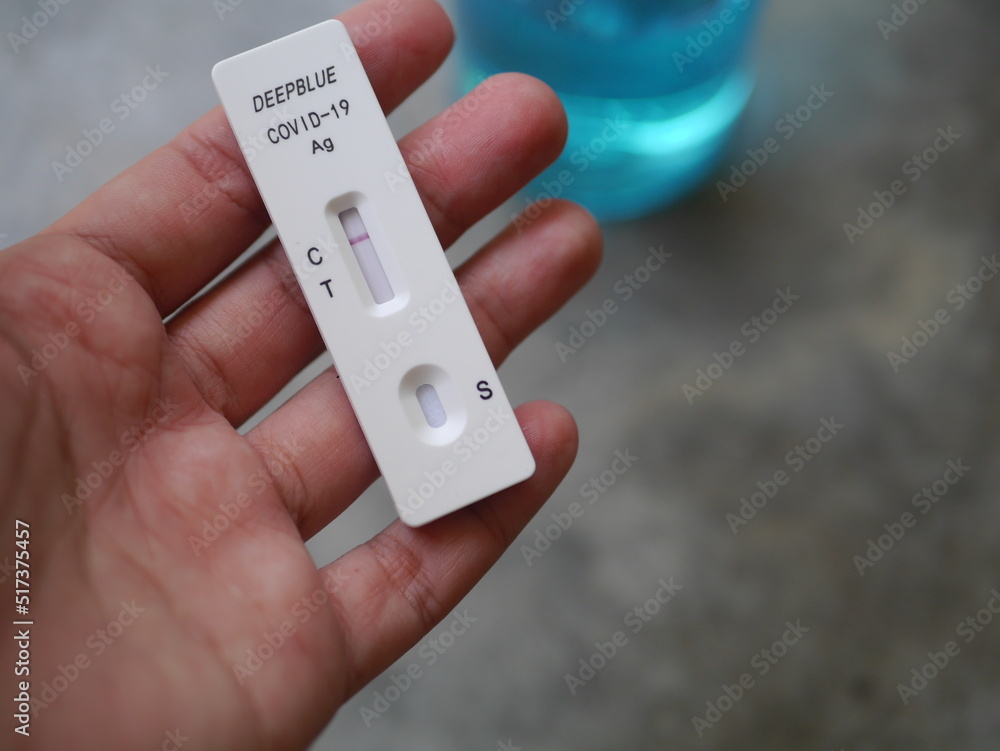 Close-up photo of hand holding Antigen test kit showing results of testing for COVID-19 test result is negative, with alcohol backdrop, ideal for illustrating COVID-19 news. Close-up photo of hand holding Antigen test kit showing results of testing for COVID-19 test result is negative, with alcohol backdrop, ideal for illustrating COVID-19 news.