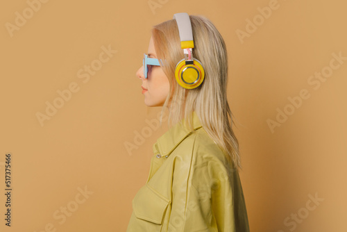 Stylish 80s woman in eyeglasses and headphones on brown background