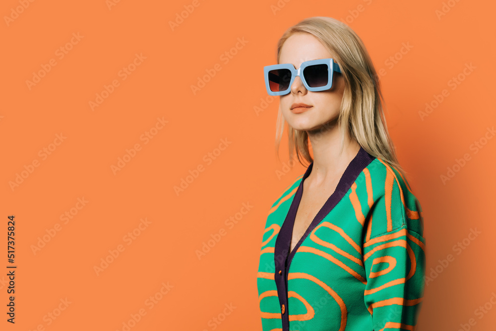 Stylish 80s woman in eyeglasses, headphones and blouse on orange background Stylish 80s woman in eyeglasses, headphones and blouse on orange background