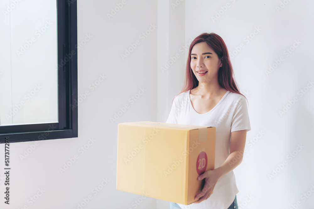 Young woman moving into new apartment holding cardboard boxes with belongings Young woman moving into new apartment holding cardboard boxes with belongings