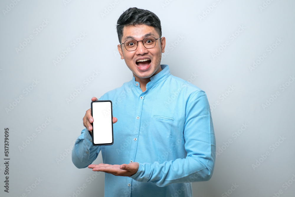 Asian guy smile looking to camera showing smartphone empty screen recommending application Asian guy smile looking to camera showing smartphone empty screen recommending application