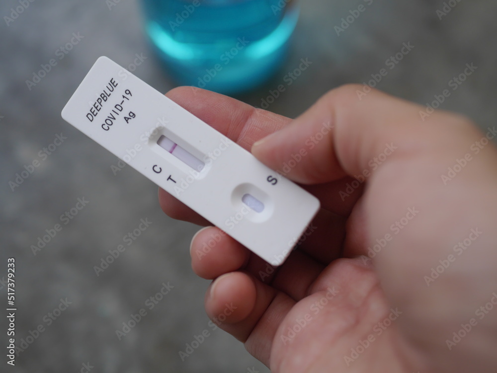 Close-up photo of hand holding Antigen test kit showing results of testing for COVID-19 test result is negative, with alcohol backdrop, ideal for illustrating COVID-19 news.