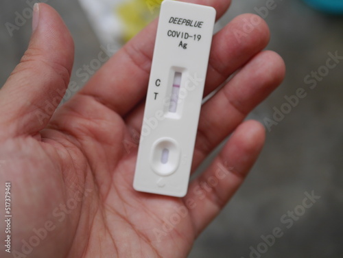 Close-up photo, hands holding Antigen test kit showing results of testing for COVID-19 test result is positive, suitable for illustrating COVID-19 news.