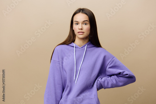 a pleasant, calm, relaxed woman stands in a purple suit on a beige background posing with her hands on her belt © Tatiana