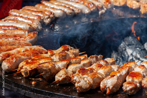 Assorted delicious grilled meat and bratwurst over the coals on a barbecue. Selective focus.