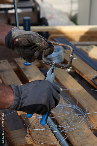 Close up photo of man holding pliers. Man works with reinforcement steel. Construction work in details. 