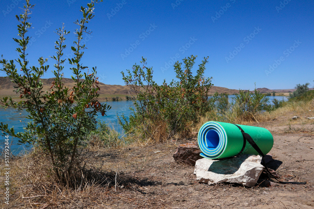 a twisted yoga mat in nature. sports with a view of the water. balance relax a twisted yoga mat in nature. sports with a view of the water. balance relax