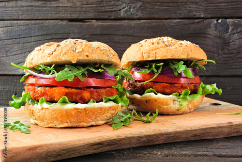 Plant based vegan burgers of chickpeas and sweet potato. Side view against a dark wood background.