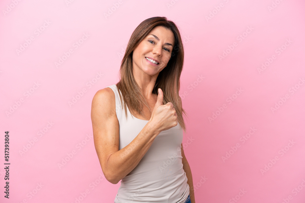Middle age caucasian woman isolated on pink background giving a thumbs up gesture Middle age caucasian woman isolated on pink background giving a thumbs up gesture