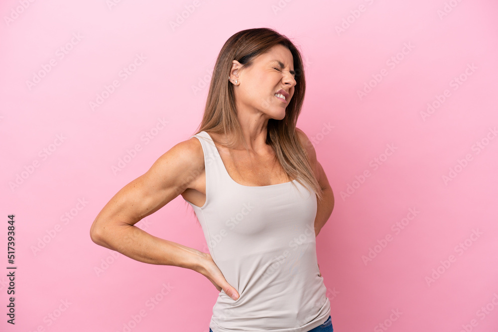 Middle age caucasian woman isolated on pink background suffering from backache for having made an effort Middle age caucasian woman isolated on pink background suffering from backache for having made an effort