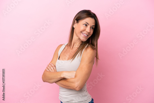 Middle age caucasian woman isolated on pink background with arms crossed and happy