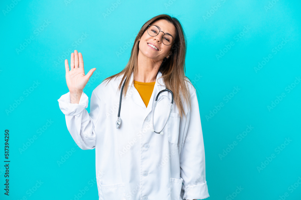 Middle age woman isolated on blue background wearing a doctor gown and saluting Middle age woman isolated on blue background wearing a doctor gown and saluting