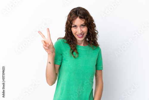 Young woman with curly hair isolated on white background smiling and showing victory sign