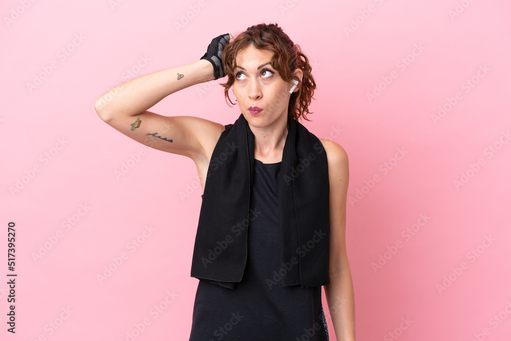 Sport sport woman with towel isolated on pink background having doubts and with confuse face expression Sport sport woman with towel isolated on pink background having doubts and with confuse face expression